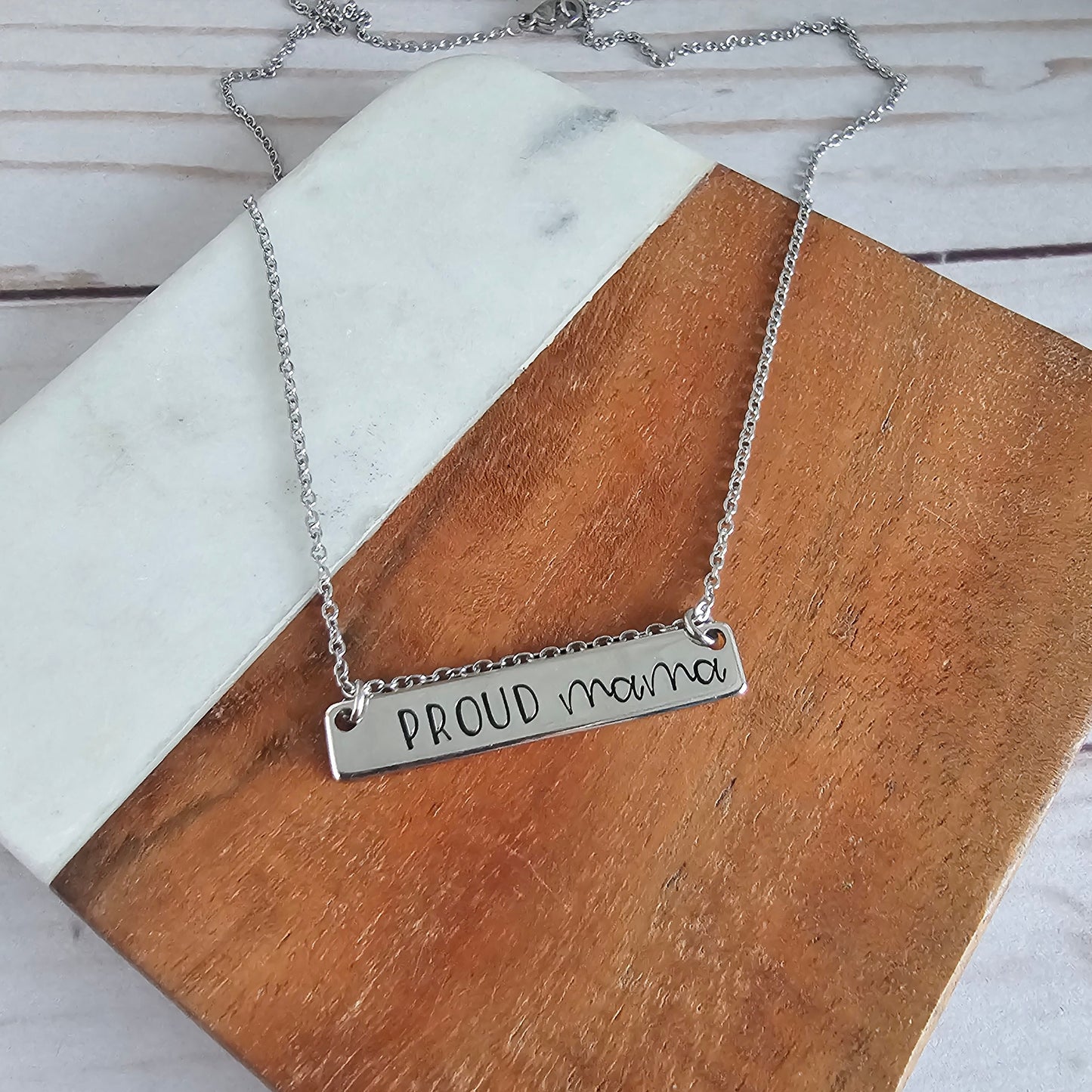 Silver horizontal bar that reads proud mama and is attached to a silver cable chain