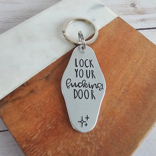 Metal keychain with engraved text on a wooden surface