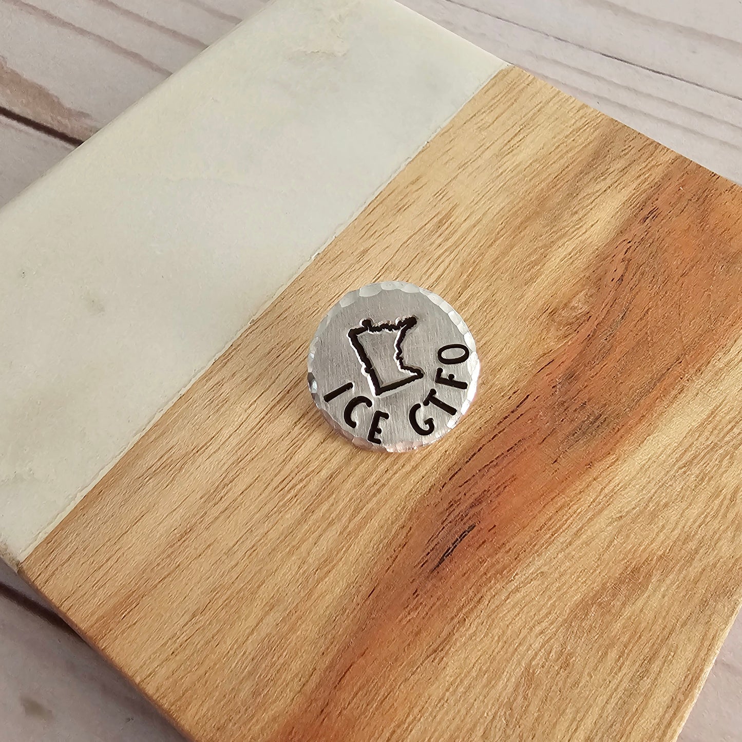 Round silver pin that reads ICE GTFO with the outline of MN