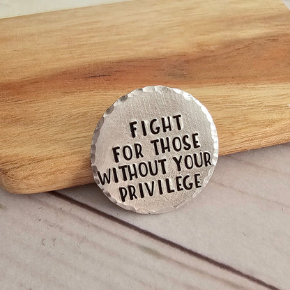 Round silver disc that reads fight for those without your privilege