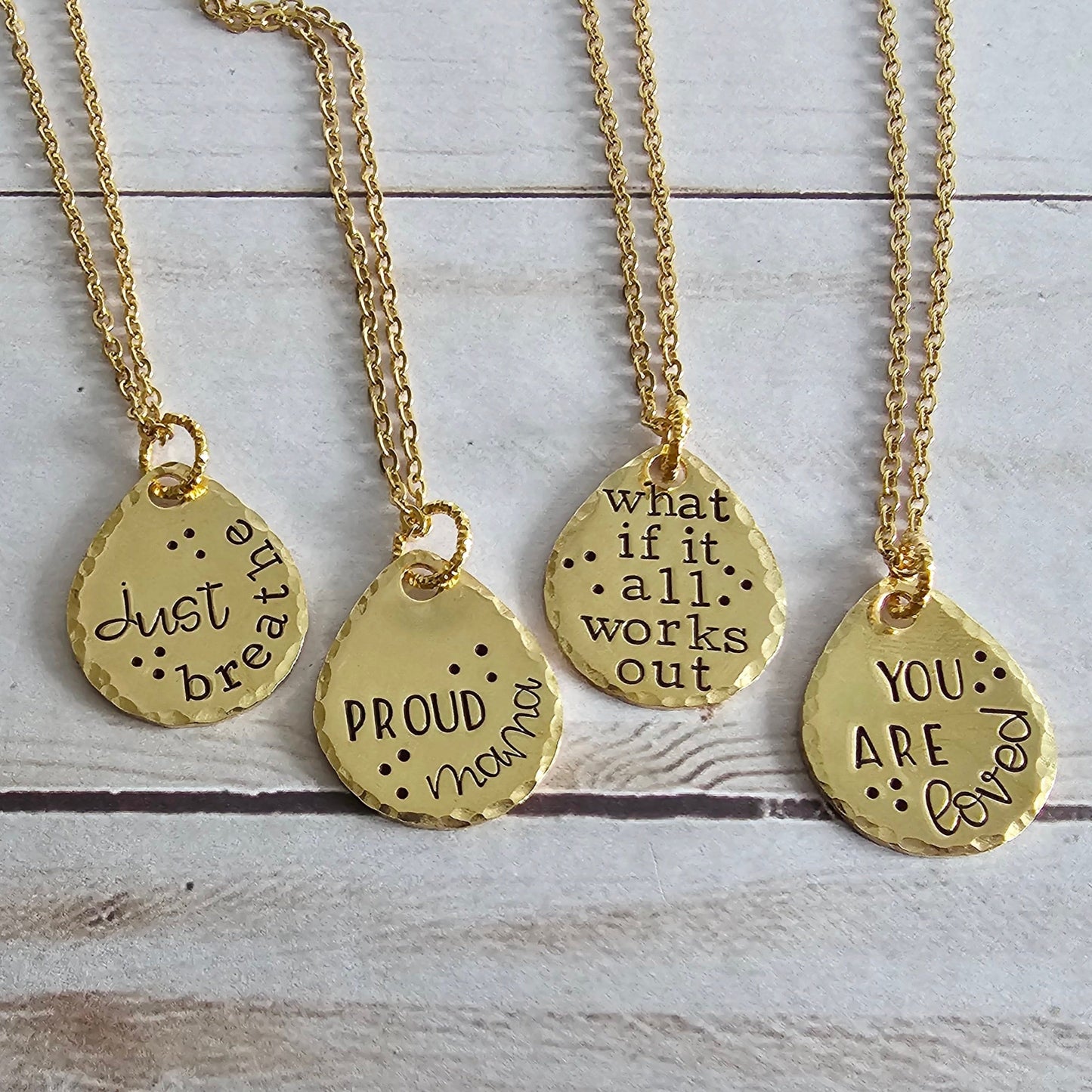 Gold tone drop shaped charm that is hand stamped with different quotes