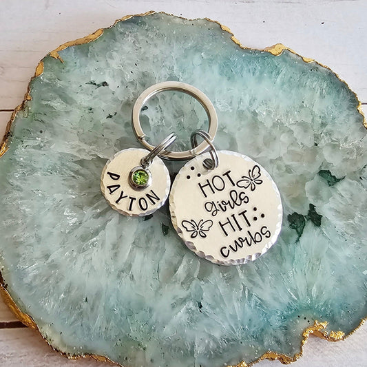 Silver metal Round Keychain that is hand stamped to read Hot Girls Hit Curbs