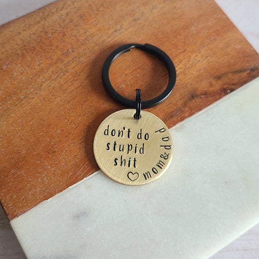 Round brass keychain that is hand stamped to read don't do stupid shit love mom and dad