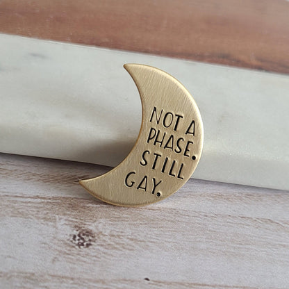 Brass Gold Crescent Moon Pin that is hand stamped to read 'not a phase. still gay.'